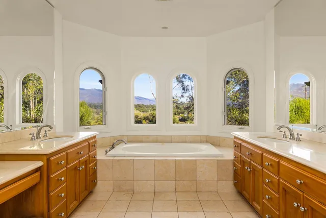 a spacious bathroom with double vanity a mirror a bathtub and a sink