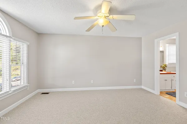 an empty room with a window and a chandelier fan