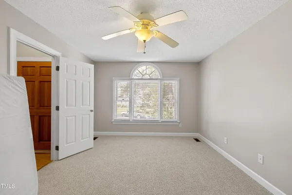 an empty room with a window and a chandelier fan