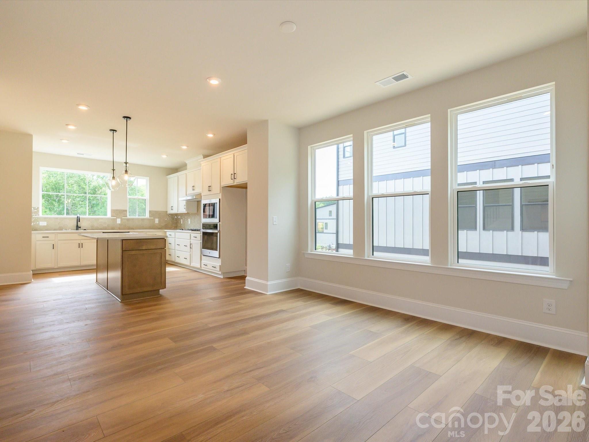 403 Old Town Vlg Road Waxhaw, NC 28173 - Photo 12 of 23 a view of an empty room with wooden floor and a kitchen