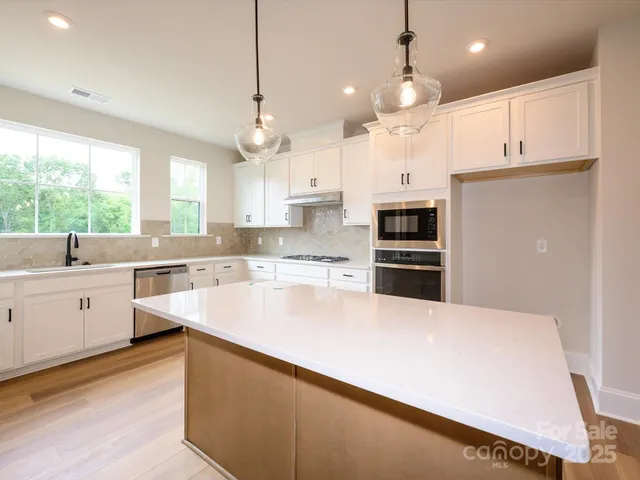 a large kitchen with cabinets a sink a window and stainless steel appliances