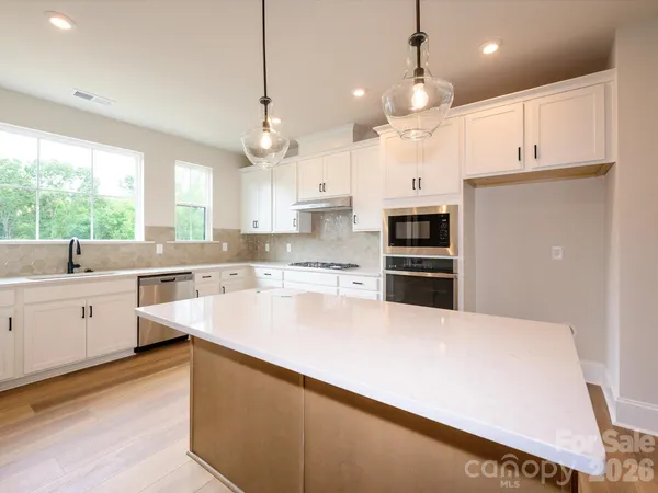 a large kitchen with cabinets a sink a window and stainless steel appliances