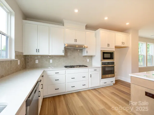 a kitchen with stainless steel appliances white cabinets and wooden floors