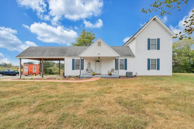 a front view of house with yard and trees in the background