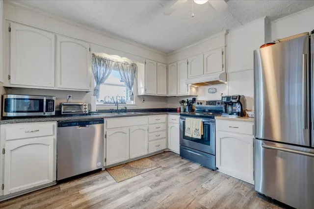 a kitchen with white cabinets stainless steel appliances and window