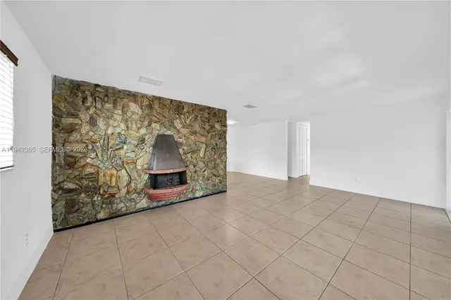 an empty room with windows and fireplace