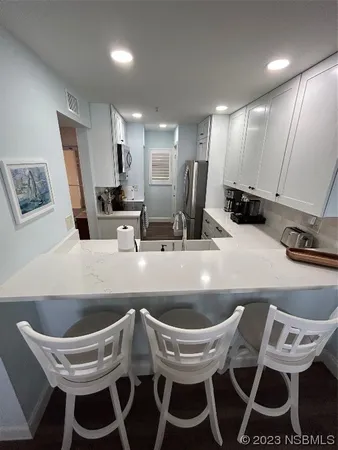 a kitchen with a dining table chairs sink and white cabinets