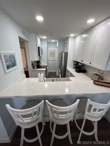 a kitchen with a dining table chairs sink and white cabinets