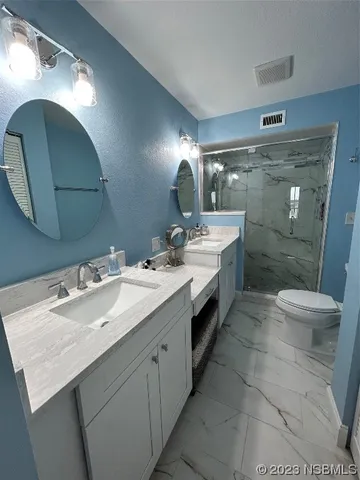 a bathroom with a double vanity sink toilet and a mirror