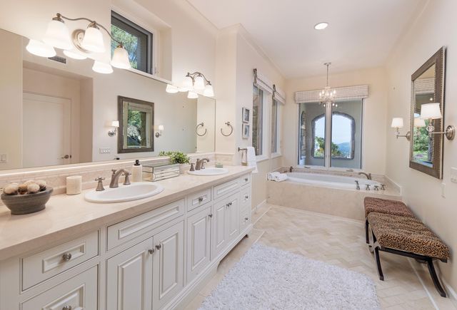 a spacious en suite bathroom with a granite countertop tub and a double vanity sink mirror