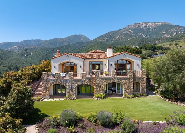 a front view of house with yard and mountain view in back