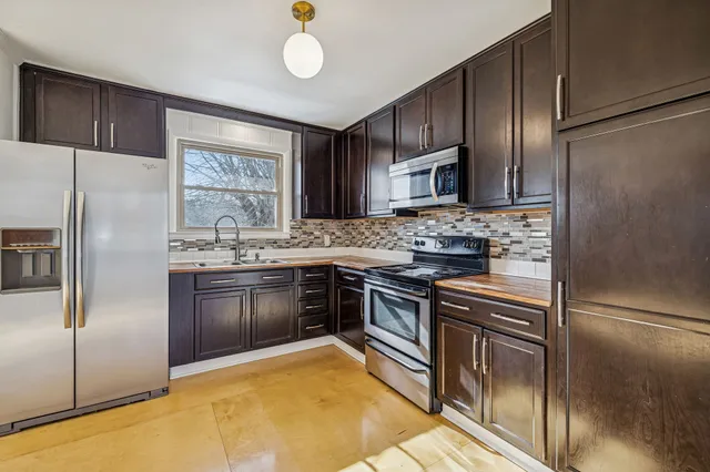 a kitchen with granite countertop stainless steel appliances a refrigerator stove top oven and sink