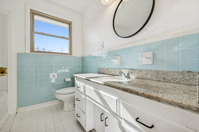 a bathroom with a granite countertop toilet sink and mirror
