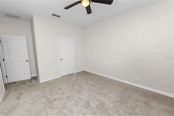 an empty room with ceiling fan and window