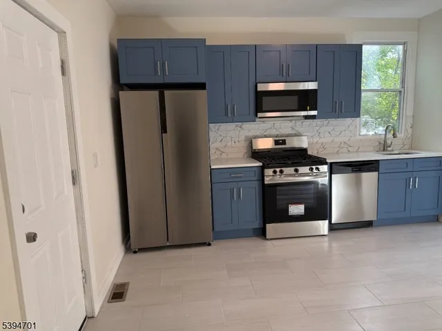 a kitchen with granite countertop a stove a refrigerator and a stove top oven