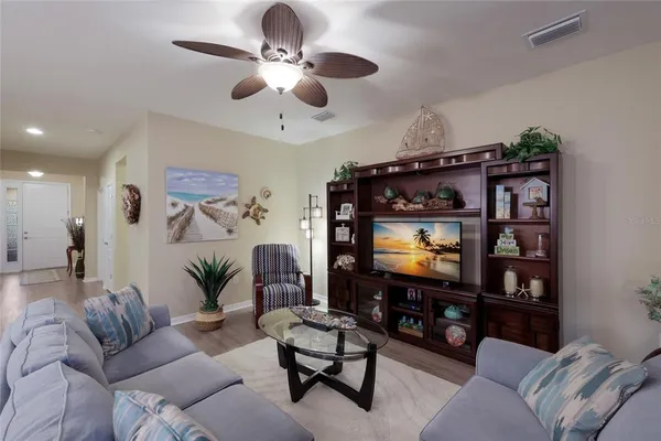 a living room with furniture a ceiling fan and a flat screen tv