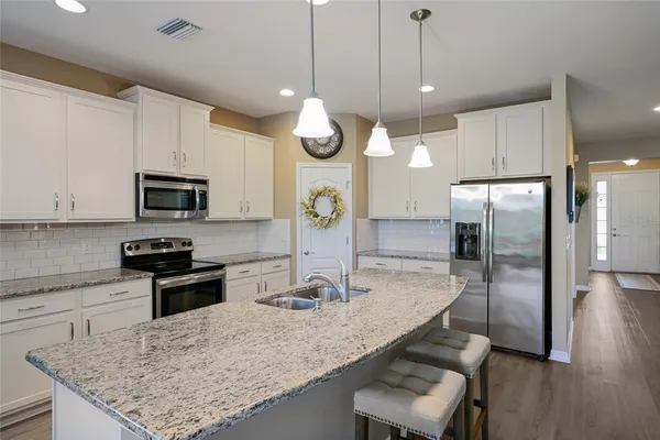 a kitchen with stainless steel appliances granite countertop a sink refrigerator and microwave