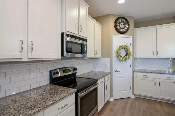 a kitchen with granite countertop a stove a microwave a sink and cabinets