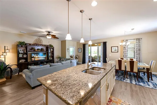 a view of a dining room and livingroom with furniture wooden floor a rug a flat screen tv a rug and a chandelier