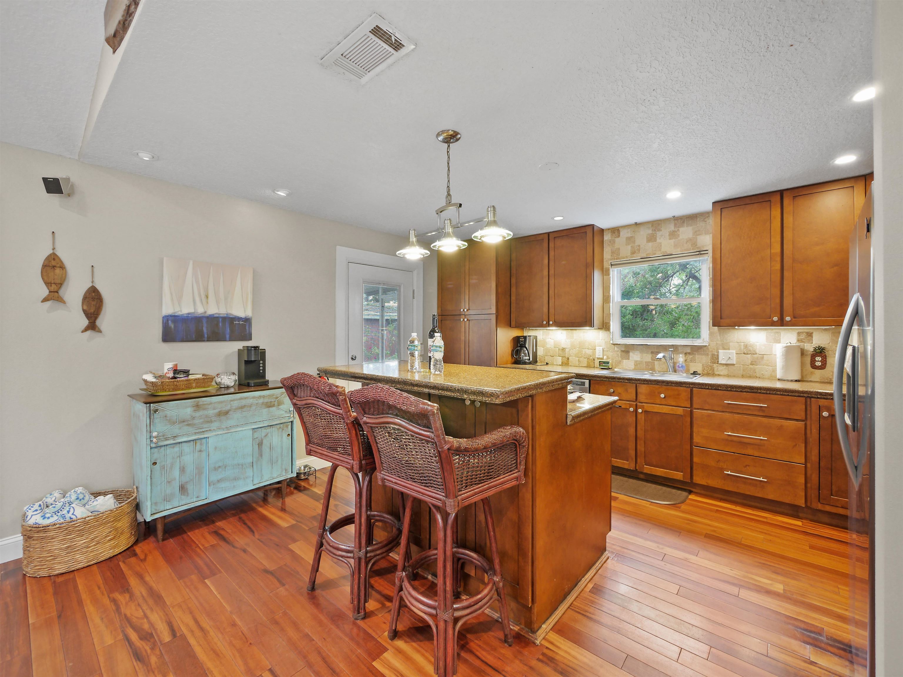 5301 1st Street St. Augustine, FL 32080 - Photo 14 of 36 a kitchen with granite countertop wooden floors cabinets and dining table