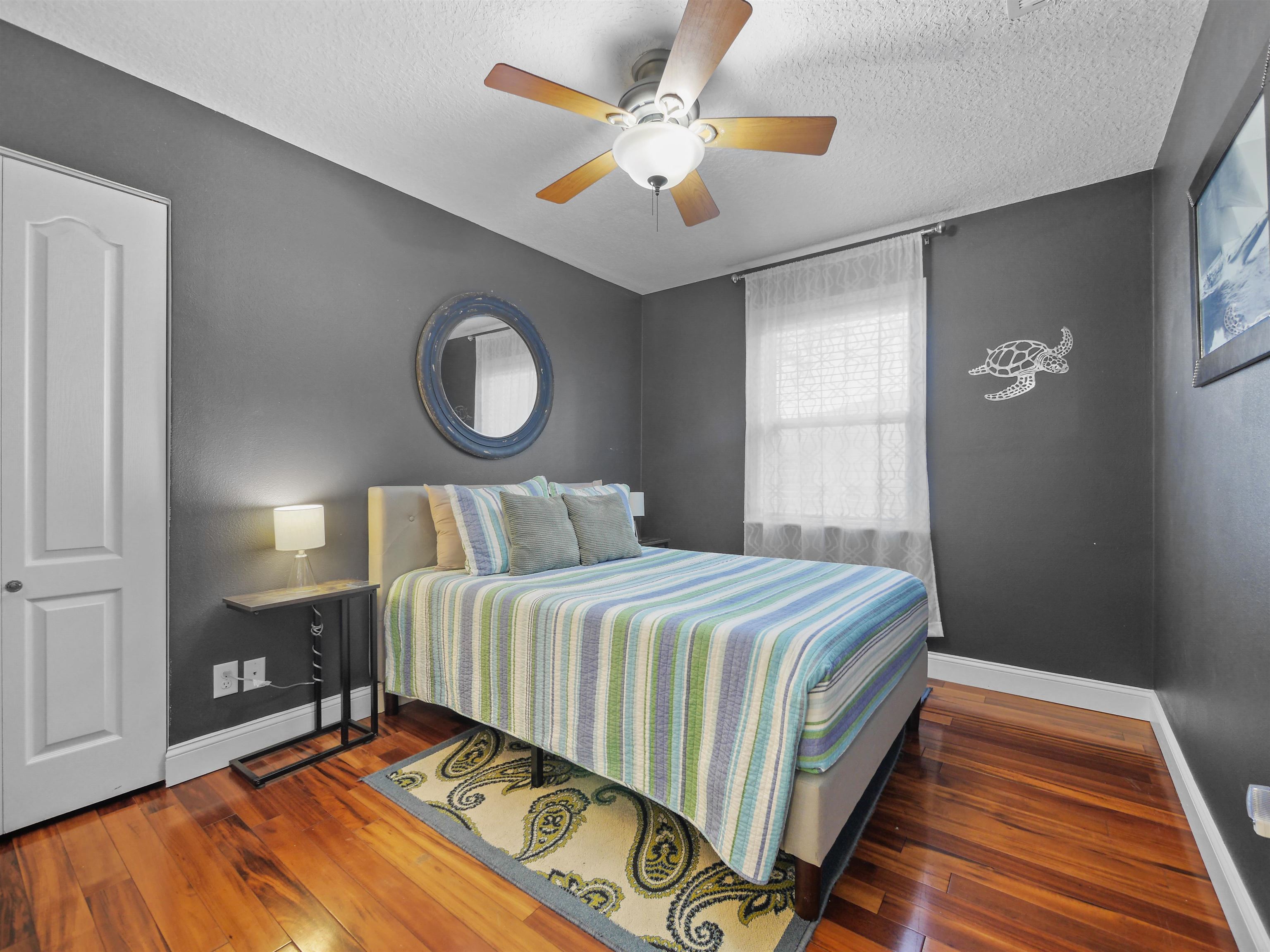 5301 1st Street St. Augustine, FL 32080 - Photo 19 of 36 a bedroom with a bed and a lamp on dresser with wooden floor