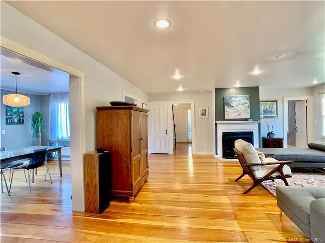 a view of a livingroom with furniture a fireplace wooden floor and windows