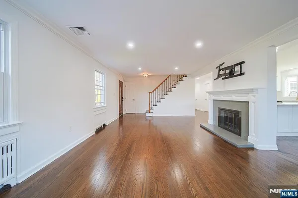 an empty room with wooden floor fireplace and windows