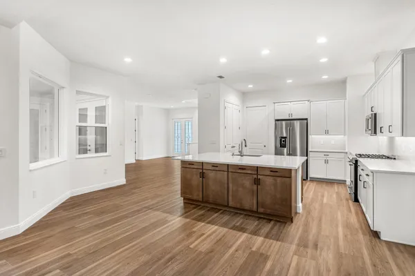 a large kitchen with kitchen island wooden floors white cabinets and stainless steel appliances