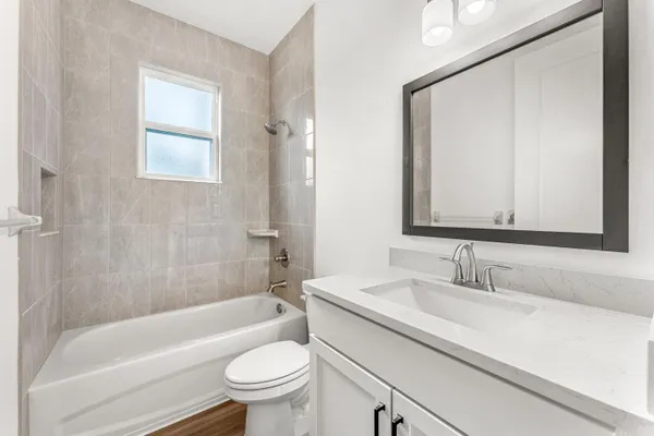 a bathroom with a bathtub shower sink vanity mirror and toilet
