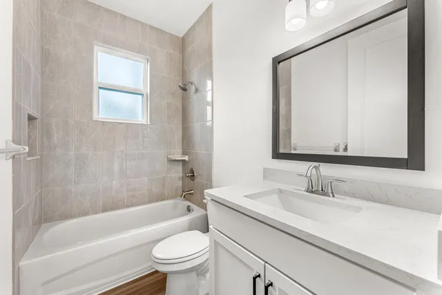 a bathroom with a bathtub shower sink vanity mirror and toilet