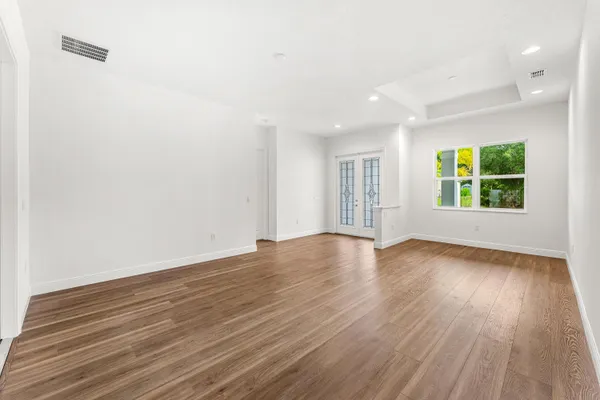 an empty room with wooden floor and windows