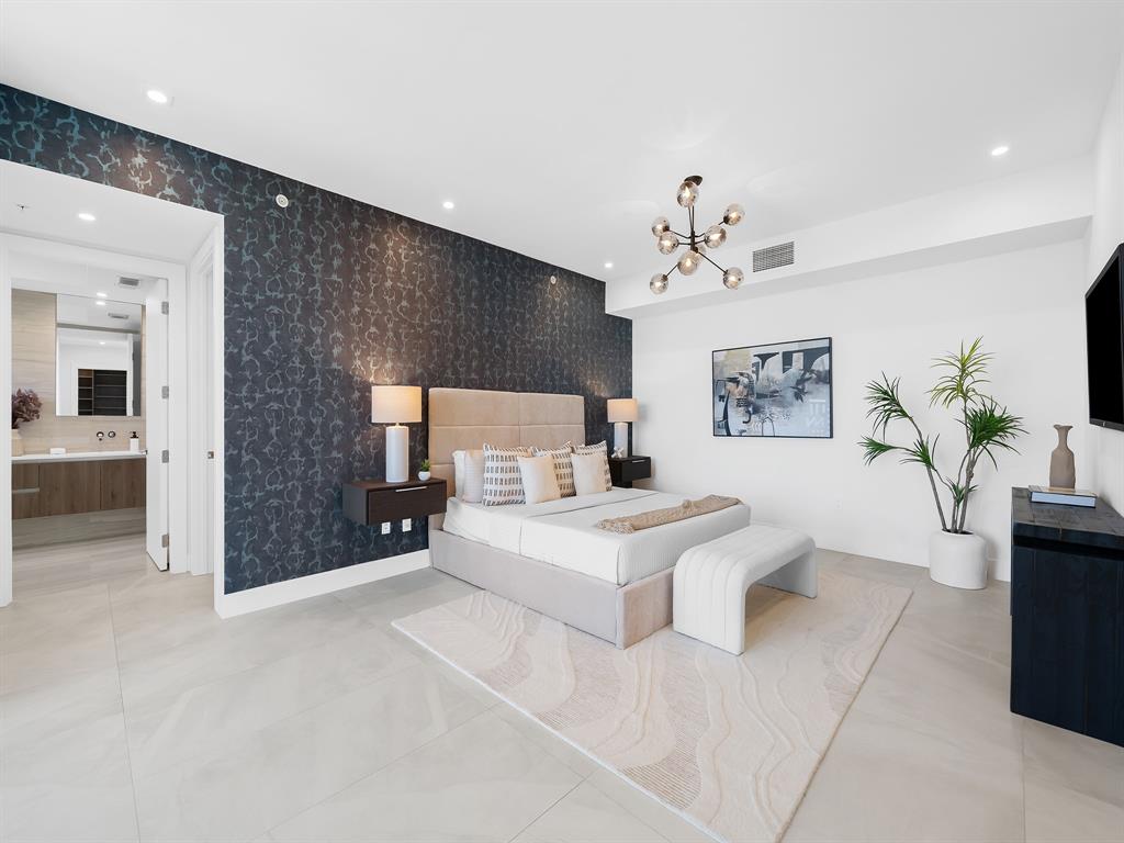 321 North Birch Road, Unit 502 Fort Lauderdale, FL 33304 - Photo 22 of 56 a spacious bedroom with a bed and a chandelier