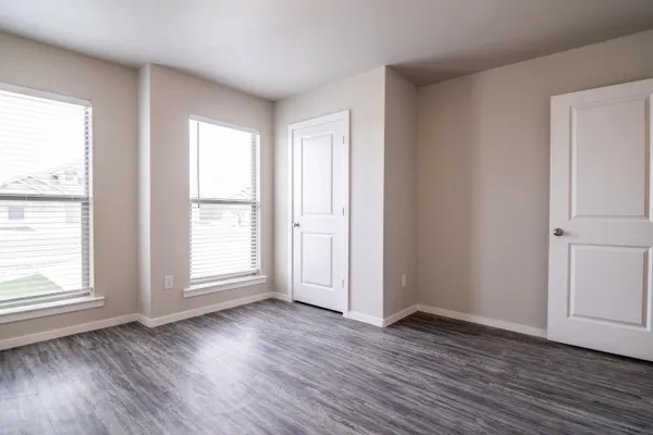 an empty room with wooden floor and windows with curtains view