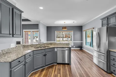 a kitchen with stainless steel appliances granite countertop a sink cabinets and wooden floor