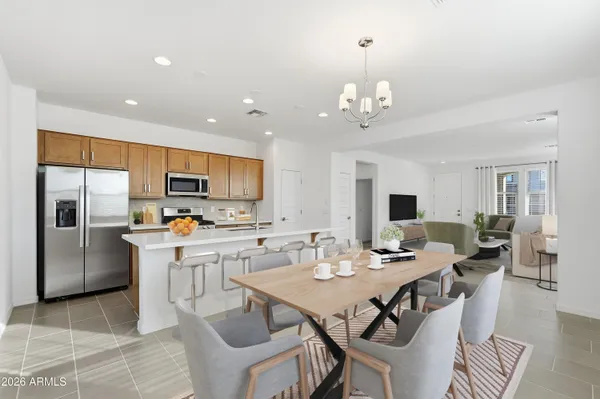 a open dining room with stainless steel appliances a dining table and chairs