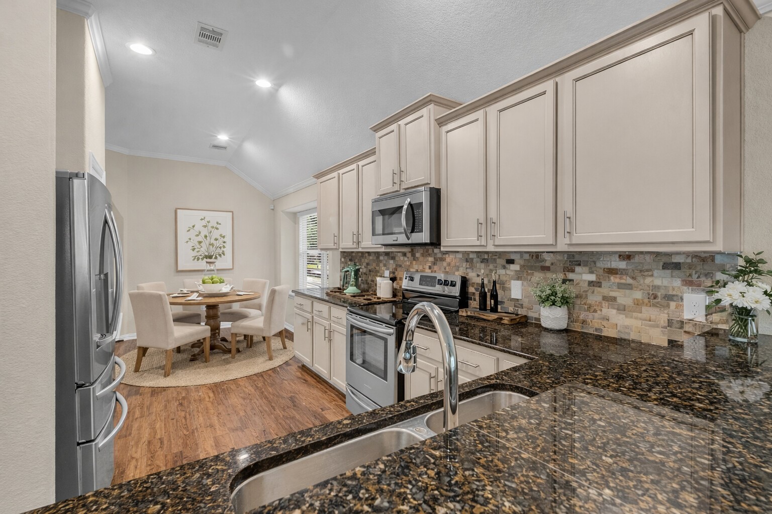 9023 South Comanche Circle Willis, TX 77378 - Photo 8 of 28 a kitchen with stainless steel appliances granite countertop a stove top oven a sink a dining table and chairs
