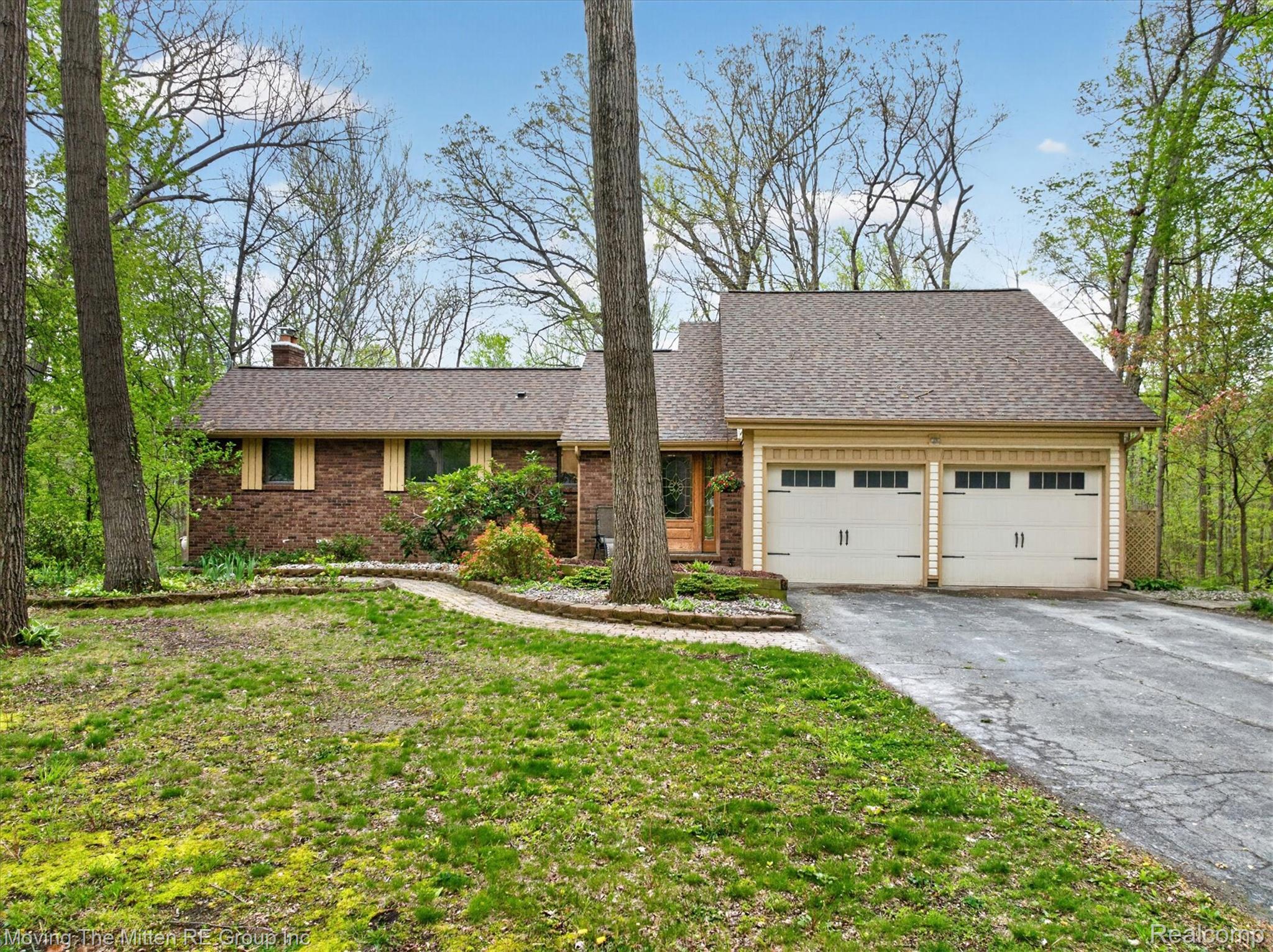 View of front of house with a garage, driveway, a chimney, and roof with shingles