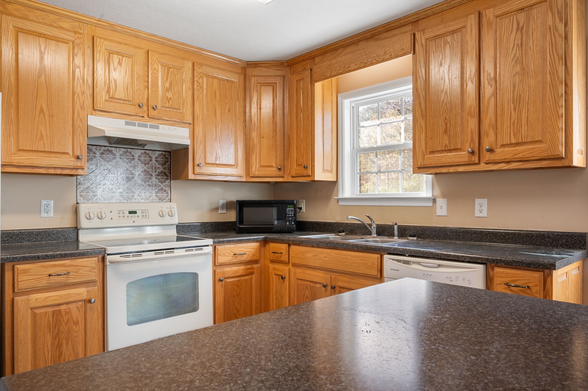 121 Wells Lee Road Elora, TN 37328 - Photo 7 of 48 a kitchen with granite countertop wooden cabinets stainless steel appliances and a window