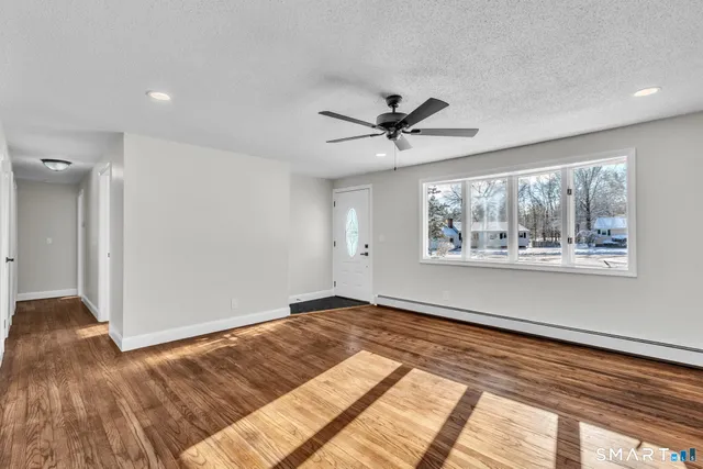 a view of an empty room with wooden floor and a window