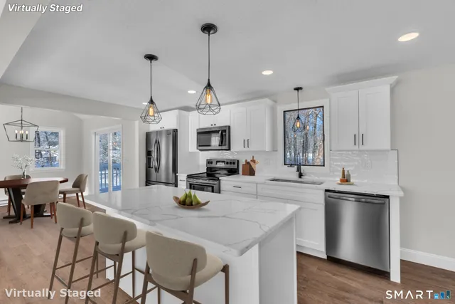 a kitchen with stainless steel appliances kitchen island granite countertop a sink a stove a dining table and chairs with wooden floor