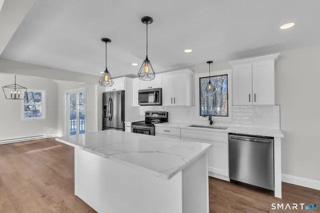 a kitchen with stainless steel appliances kitchen island granite countertop a sink a counter space and cabinets