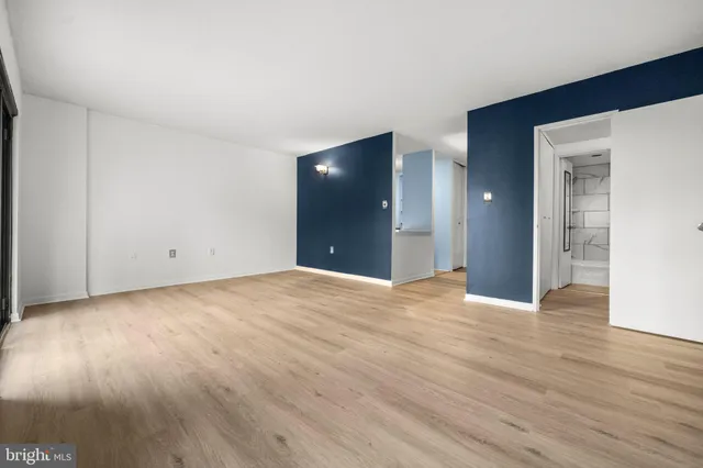 a view of an empty room with wooden floor and closet