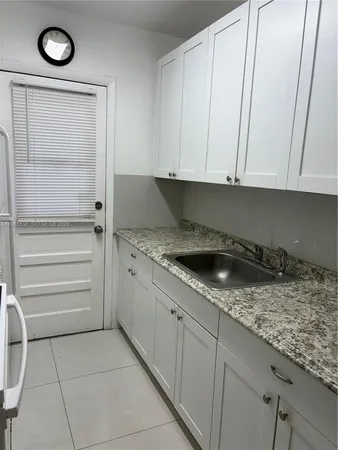 a kitchen with granite countertop white cabinets and a stove