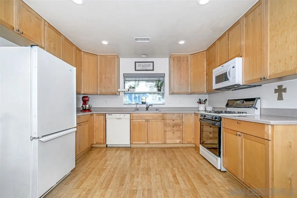 8311 Sunset Road Lakeside, CA 92040 - Photo 4 of 25 a kitchen with stainless steel appliances granite countertop a refrigerator a stove top oven and a sink with wooden floors