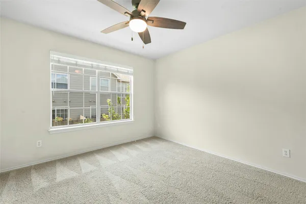 an empty room with a window and a fan