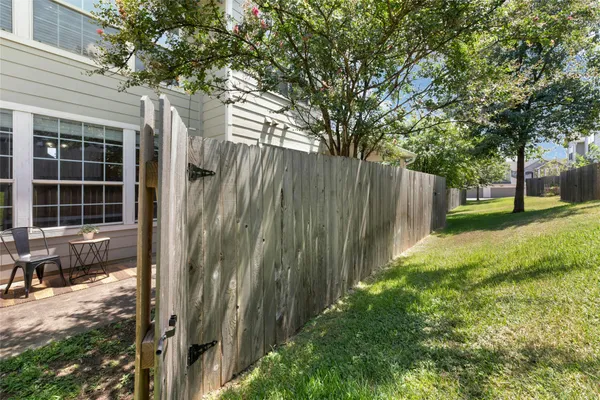 a view of a backyard with large trees and wooden fence