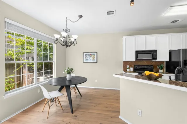 a kitchen with stainless steel appliances granite countertop a stove top oven a refrigerator a sink dishwasher a dining table and chairs with wooden floor