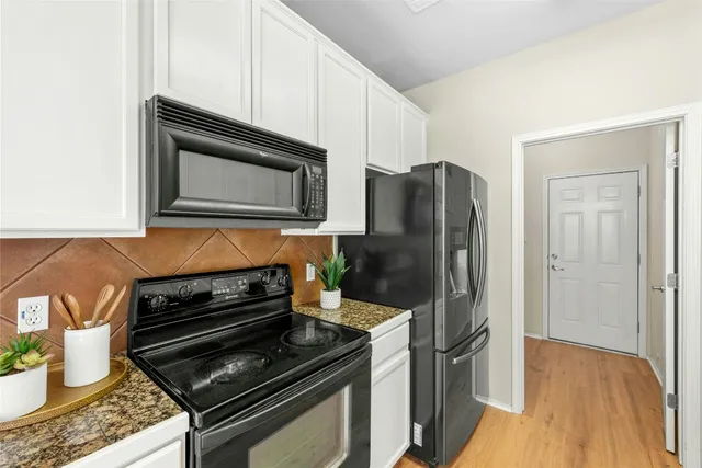 a kitchen with granite countertop a stove and a microwave with wooden floor