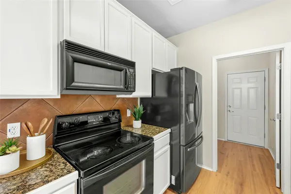 a kitchen with granite countertop a stove and a microwave with wooden floor