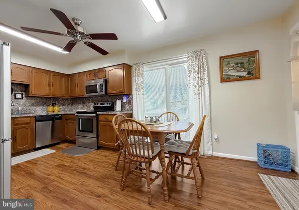 a view of a dining room with furniture a ceiling fan and wooden floor